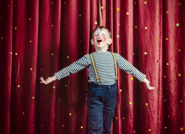 Young,Boy,Dressed,As,Clown,Performing,On,Stage,With,Open