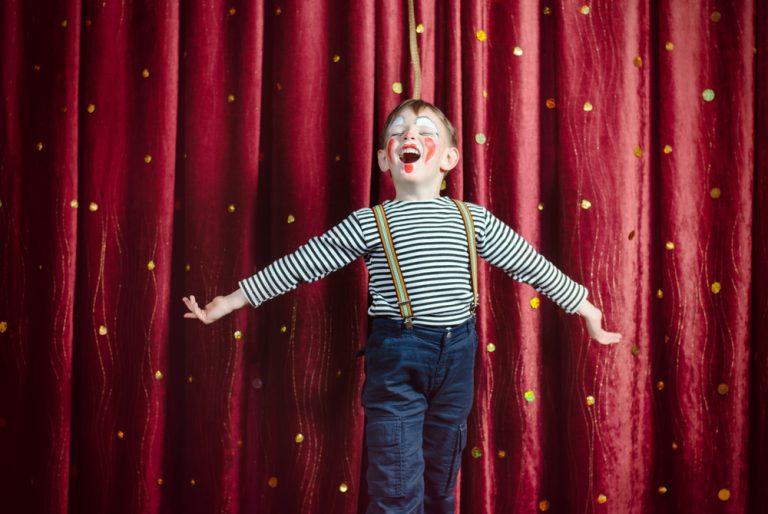 Young,Boy,Dressed,As,Clown,Performing,On,Stage,With,Open